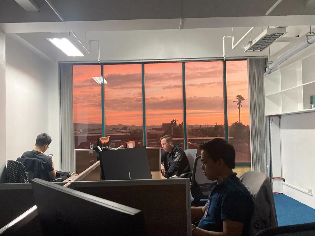 Operators at their desks with a sunset through the office windows