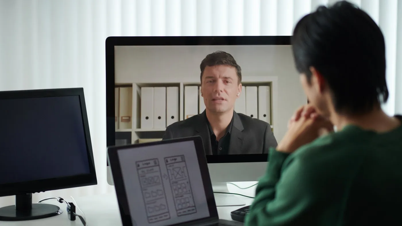 A candidate interviewed over video, with design work samples open on a laptop